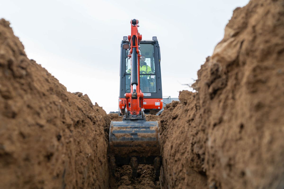 Bagger gräbt Graben für Glasfaserverlegung